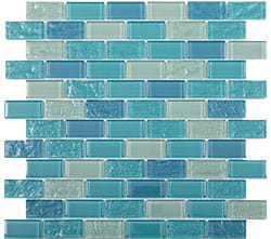 A glass mosaic tile sheet featuring small rectangular tiles in various shades of blue and teal, arranged in a staggered brick pattern. The tiles have a glossy and textured finish.