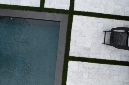 White Mist sandblasted marble pavers surrounding a modern swimming pool